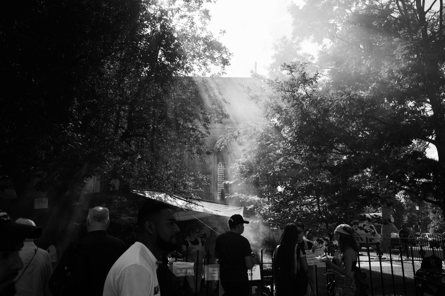Woman laughing mid-song in a street-party crowd, candid black and white