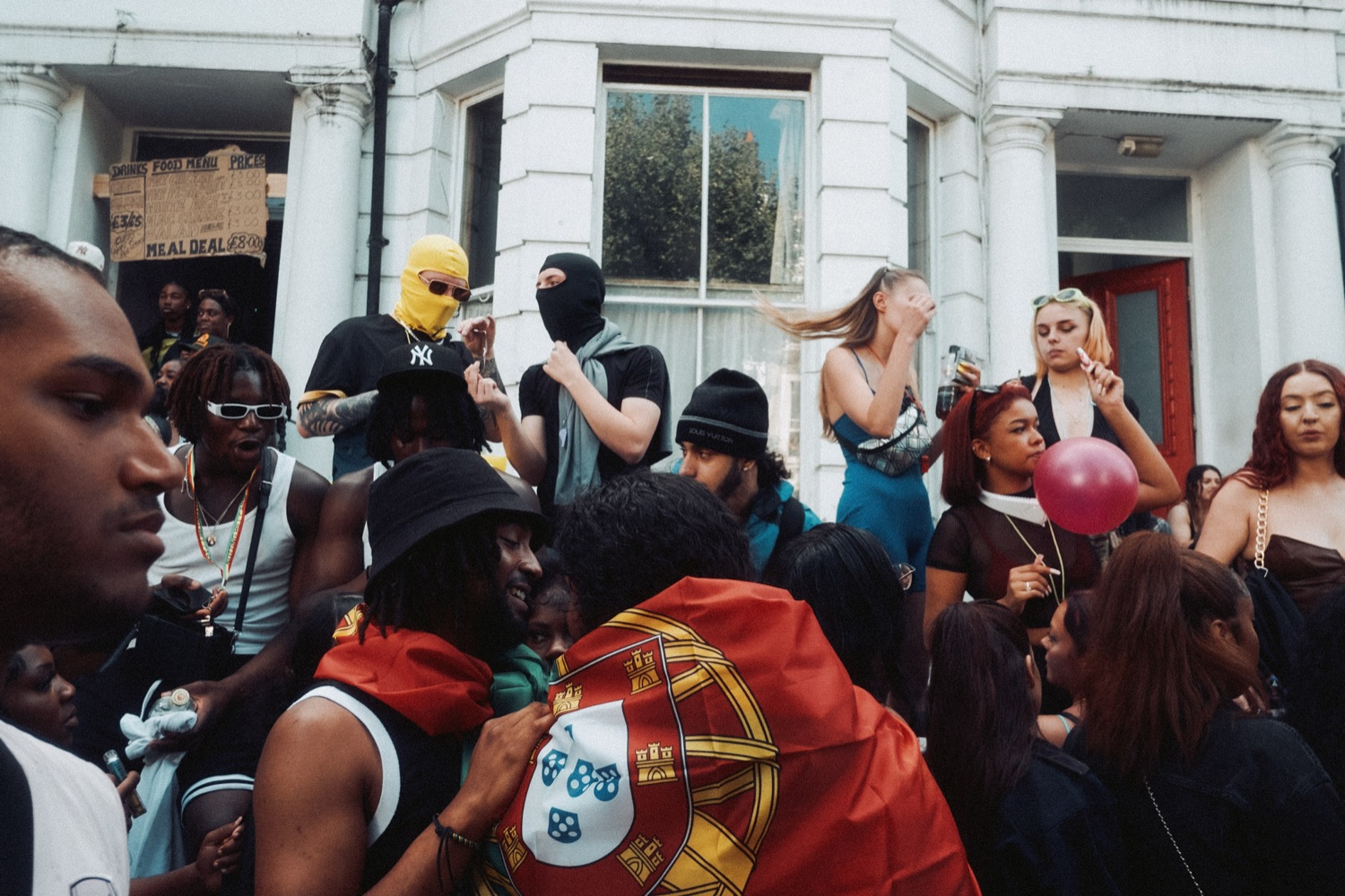 Street party in golden hour — laughter in front, an embrace behind